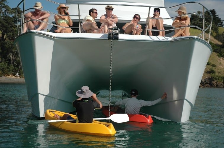 Guests kayaking between the twin hulls of Kozmic 5